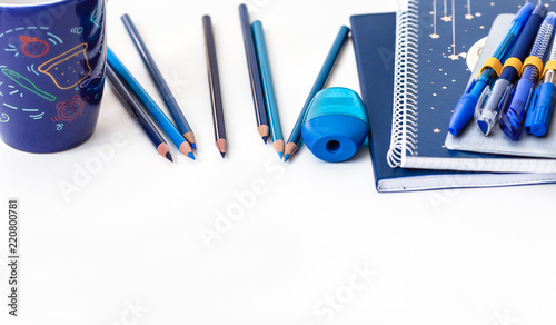 Back to school blue items on white background. Allin blue colors: Notebook, cup, pens, set of pencils and pencil sharpener. photo