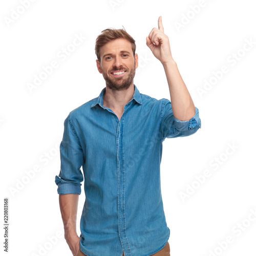 smiling casual man with one hand in pocket points up photo