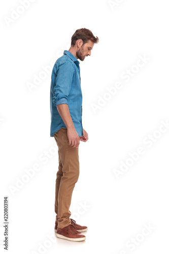side view of a casual man looking down at something