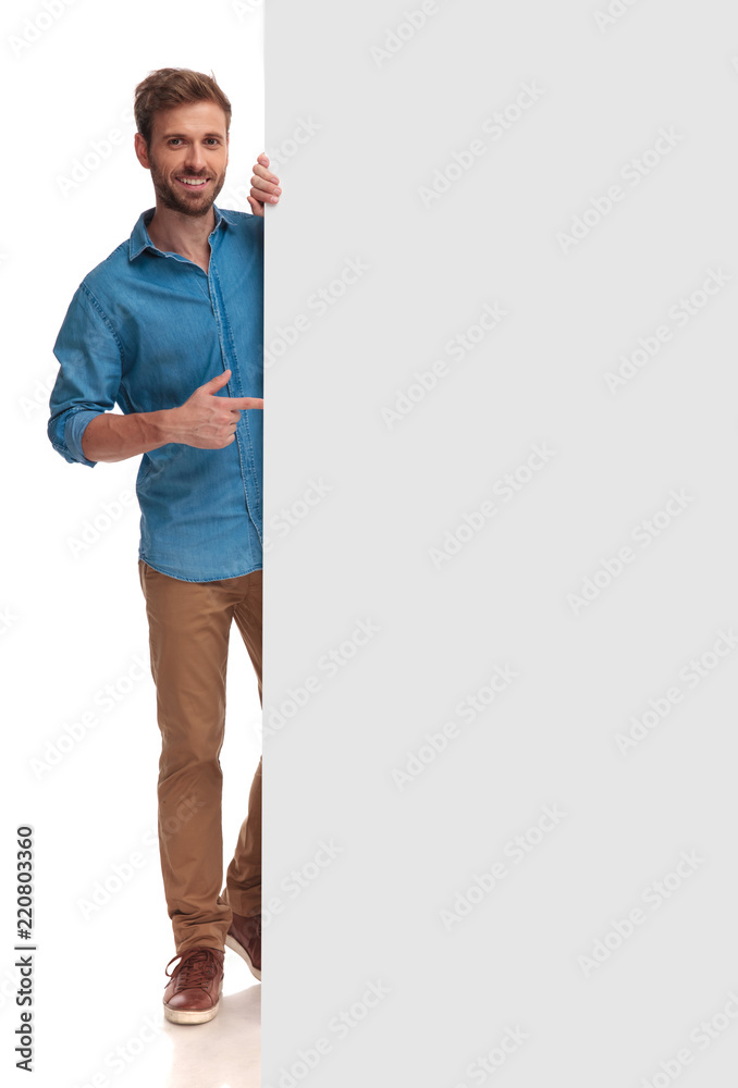happy casual man poiting finger at a blank board - obrazy, fototapety, plakaty 