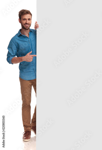 happy casual man poiting finger at a blank board photo