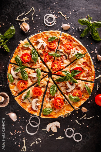 Flat lay with Italian pizza on black background and various ingredients