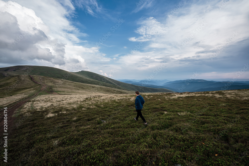 Young man walking on a hill road. Carpathians, Ukraine