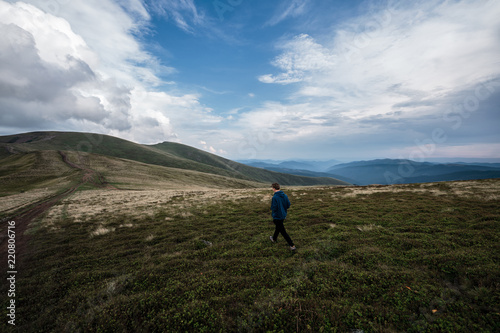 Young man walking on a hill road. Carpathians, Ukraine