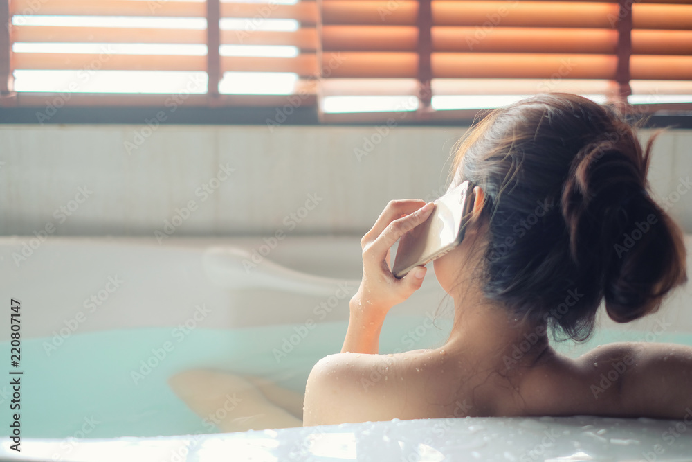 Woman calling smartphone in bathtub, selective focus, relax concept.
Woman calling smartphone in bathtub, selective focus, relax concept.