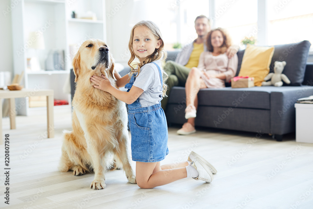 Cute little girl touching and cuddling labrador dog while looking at camera Cute little girl touching and cuddling labrador dog while looking at camera
