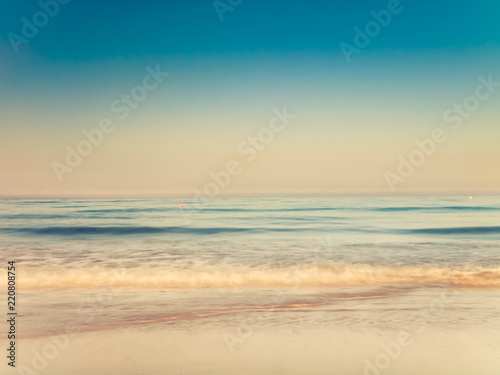 motion blurred gentle waves splashing in the morning on the sand beach