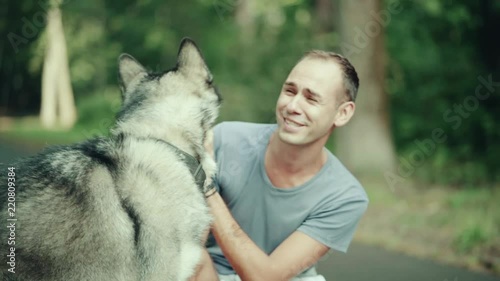 A man in park stroking a dog photo