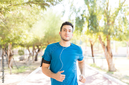 Athletic Male Listening Music While Running In Park