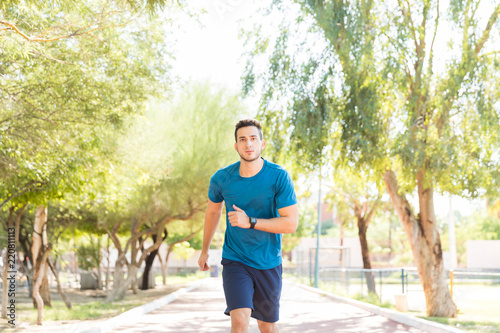Healthy Man Jogging Determinedly On Track In Park