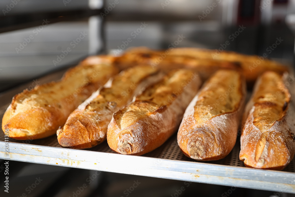 Many French baguettes on a baking sheet in the bakery Many French baguettes on a baking sheet in the bakery