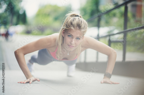 Blonde sport women exercise pushups at street.