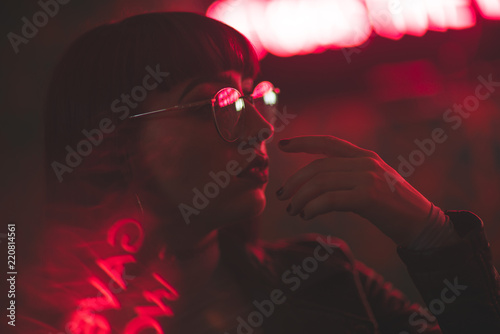 Young redhead dancer with glasses on neon lights