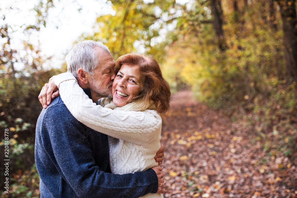 A senior couple hugging in an autumn nature, kissing. Copy space. A senior couple hugging in an autumn nature, kissing. Copy space.