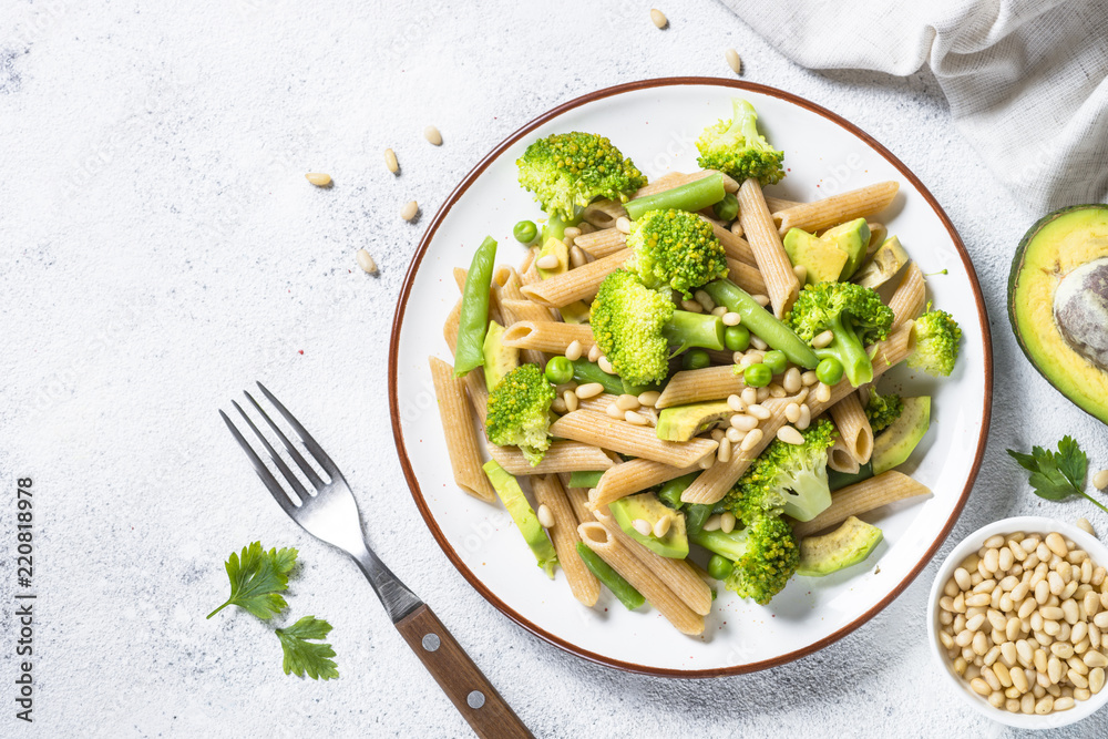 Vegan pasta penne with broccoli, avocado and pine nuts top view. Vegan pasta penne with broccoli, avocado and pine nuts top view.
