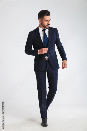 young businessman walking and buttoning his navy suit photo