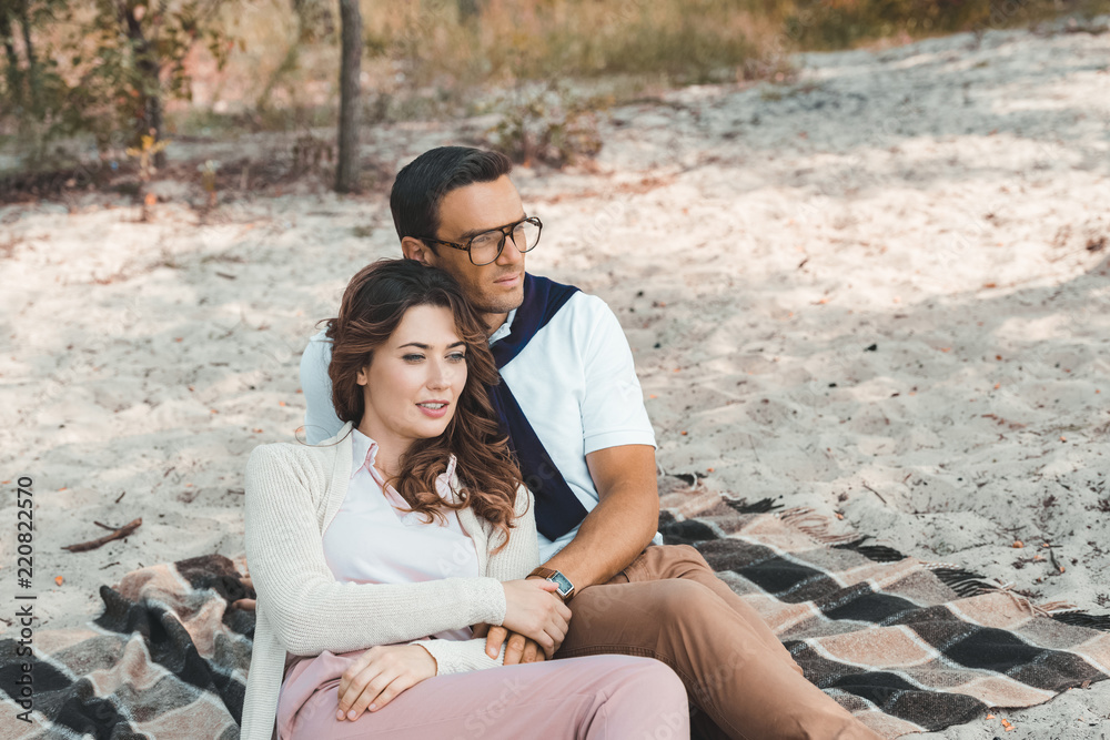 Obraz premium romantic couple resting on blanket on sandy beach