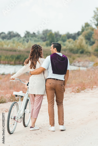 back view of couple with retro bicycle on sandy beach