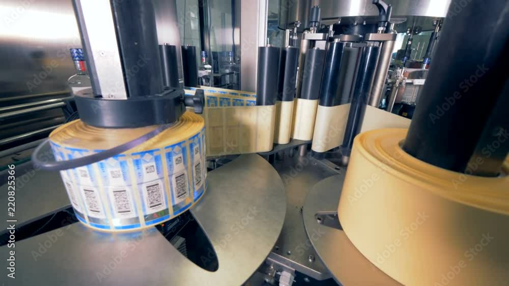 Rolls of tags for bottles. Special machine spins, putting tags on bottles at a plant.