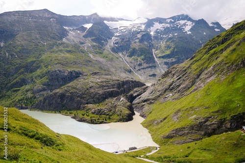A blue mountain lake between the green slopes of the mountains. Grossglockner Hochalpenstrasse, Austria. Summer day.