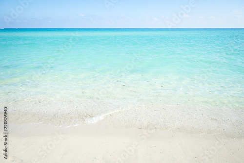 Calm clear tropical turquoise water lap at a white sandy beach