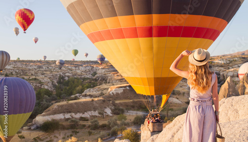 Hipster Traveler with backpack and outspread hands. Enjoying the view of the hot air balloons