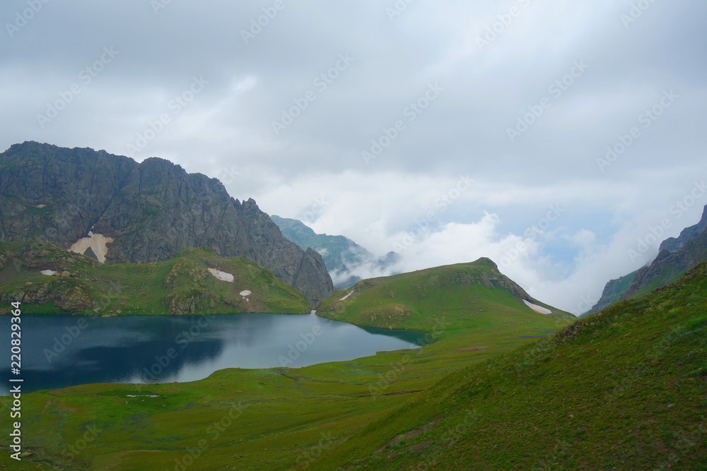 Tobavarchkhili lake with a snowy mountain pass in Caucasus Mountains on a hike to Silver Lakes in Georgia