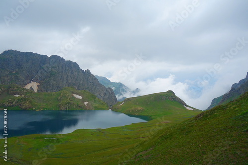 Tobavarchkhili lake with a snowy mountain pass in Caucasus Mountains on a hike to Silver Lakes in Georgia