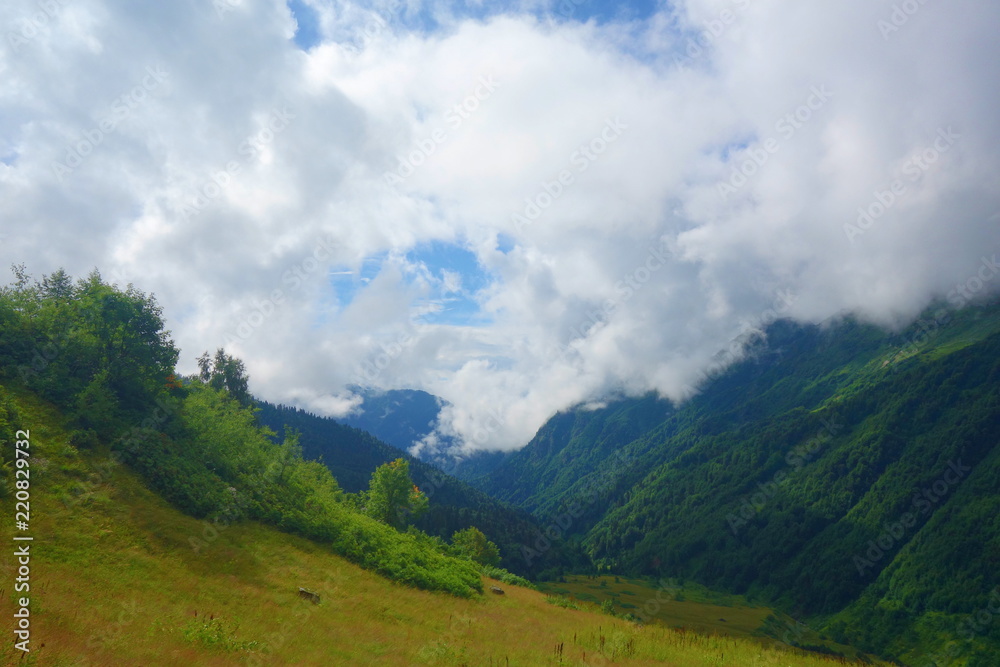 Hiking trail to Silver lakes with clouds around the mountains going via Tobavarchkhili from Mukhuri to Khaishi in Caucasus mountains, Georgia