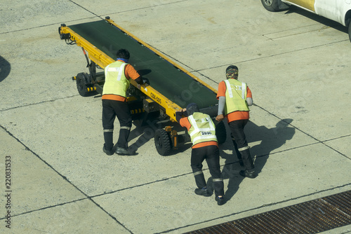 Airport ground staff moving mobile luggage belt machine 