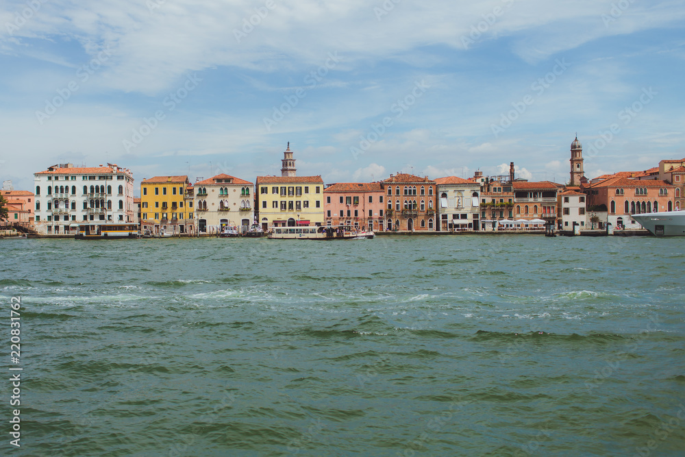 Venetian channel view at the city in one horizontal line of urban architecture, buildings, one of the Venice Bridge, free space