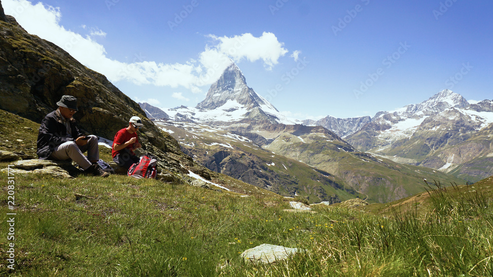 Fototapeta premium Father and Son Taking Break From Hiking in Swiss Mountains With Iconic Matterhorn Mountain in Background - Model Released