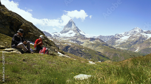 Father and Son Taking Break From Hiking in Swiss Mountains With Iconic Matterhorn Mountain in Background - Model Released
