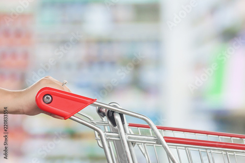 Empty red shopping cart with Pharmacy drugstore blur abstract backbround with medicine and healthcare product on shelves