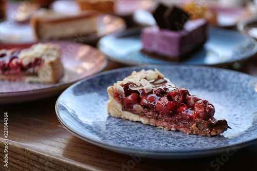Plate with slice of cherry cake on wooden table