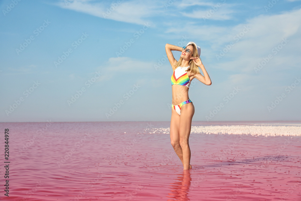 Naklejka premium Beautiful woman posing in pink lake on sunny day