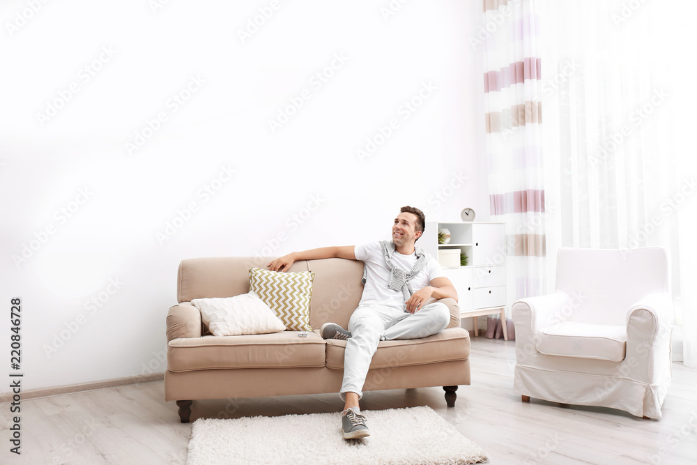 Happy young man sitting under air conditioner at home Happy young man sitting under air conditioner at home