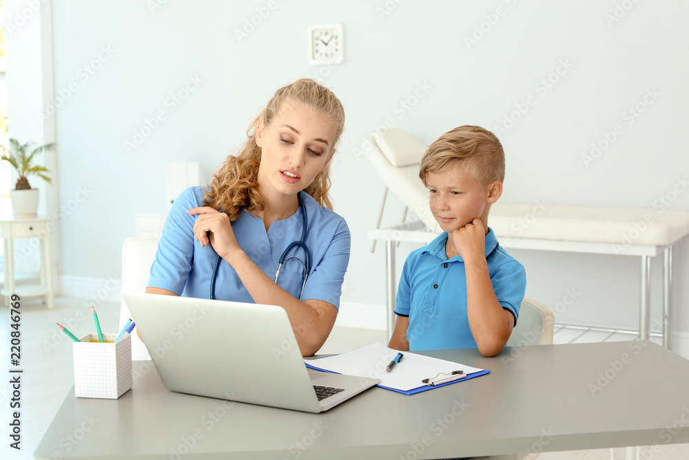 Female medical assistant explaining physical examination result to child in clinic Female medical assistant explaining physical examination result to child in clinic