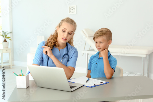 Female medical assistant explaining physical examination result to child in clinic