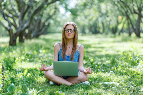 beautiful girl sitting in the Park with her laptop in Lotus position