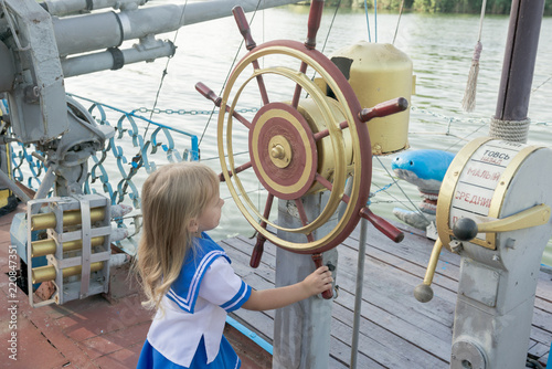 A child, a little girl in the role of captain at the helm.