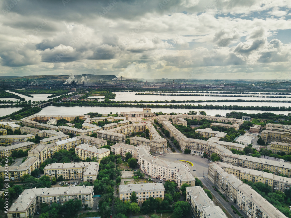 Aerial drone panoramic view of historical city center Magnitogorsk, single style of buildings architectural ensembles of 50s with gardens inside, factory and pipes on the background, Magnitogorsk Aerial drone panoramic view of historical city center Magnitogorsk, single style of buildings architectural ensembles of 50s with gardens inside, factory and pipes on the background, Magnitogorsk