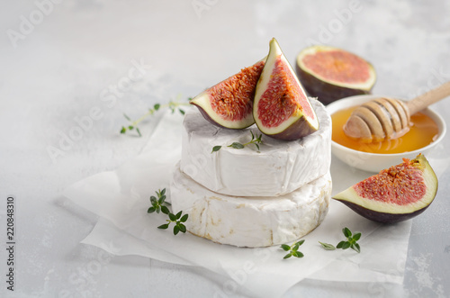 Brie or camembert cheese with figs, thyme, honey and nuts, selective focus.