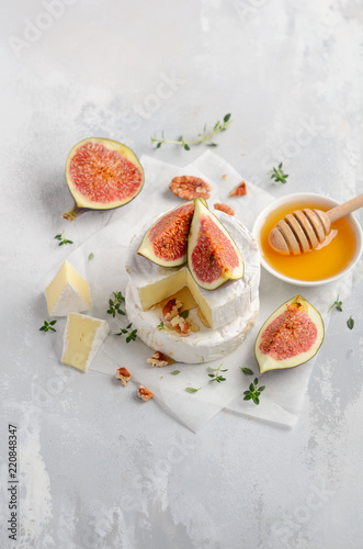 Brie or camembert cheese with figs, thyme, honey and nuts, selective focus.