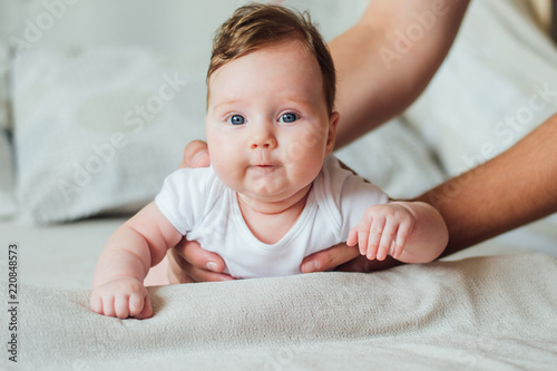 Canvas Print Parent supporting his baby while lying on a tummy