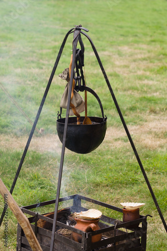 A medieval cauldron or cooking pot suspended on a hanger over an open fire