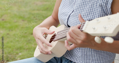 Woman play a song on ukulele at park