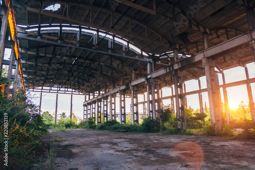 Sunset at ruined abandoned overgrown industrial building