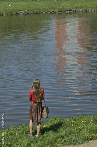 samotna dziewczyna z torebką patrzy w odbicie na wodzie, smutek i zamyślenie w czasach pandemii