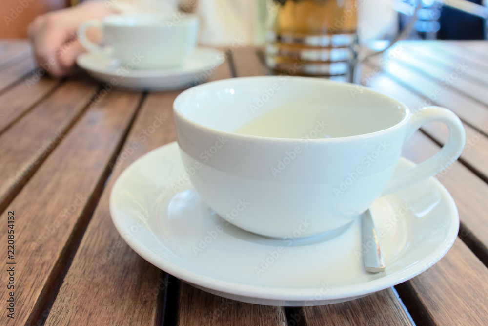 Two teacups and French press on the table, blurred woman behind. Two teacups and French press on the table, blurred woman behind.
